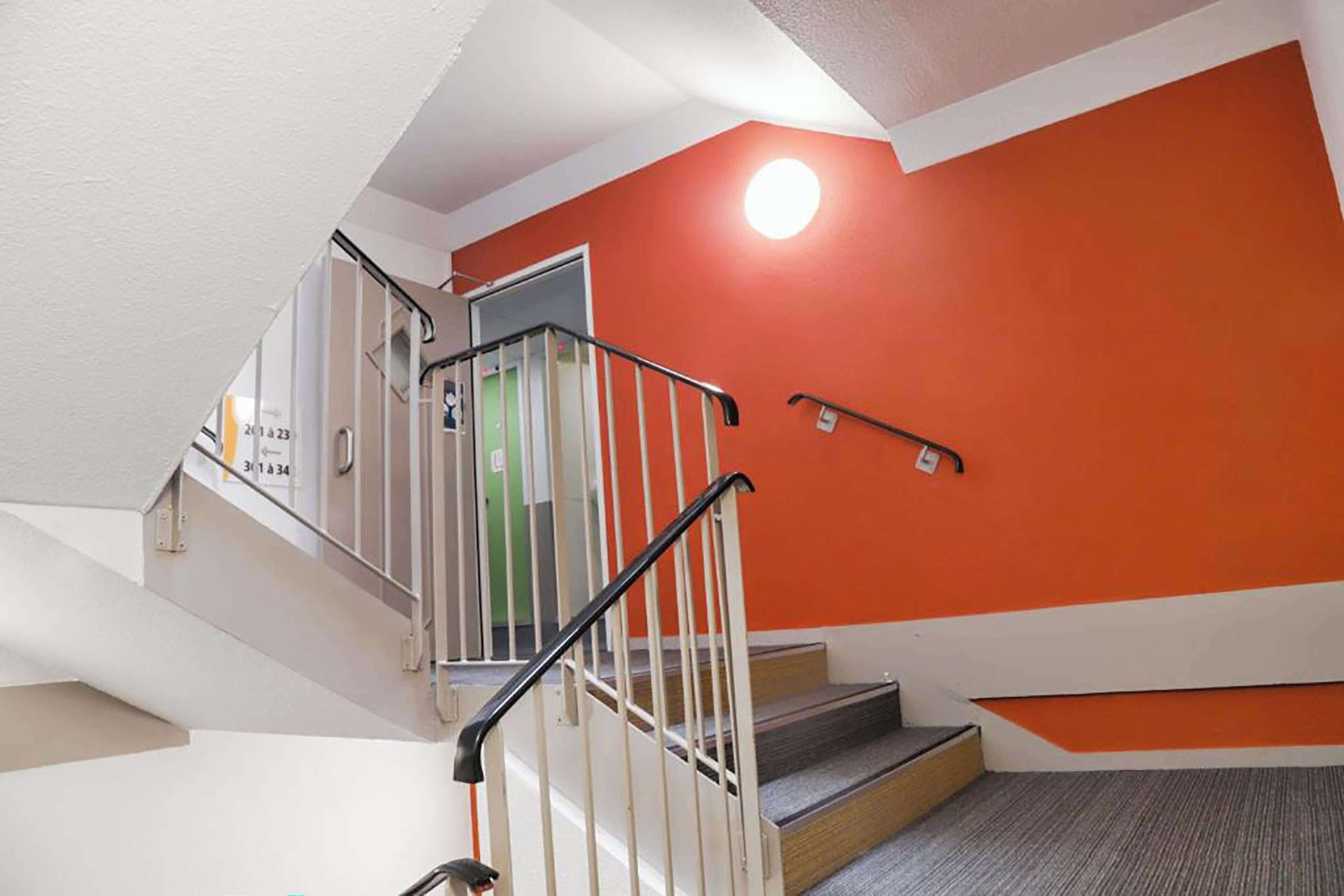 A staircase with a white railing and a red wall.