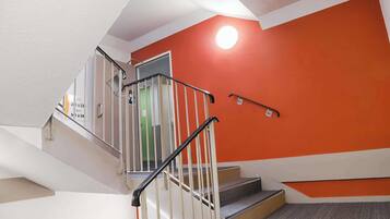 A staircase with a white railing and a red wall.