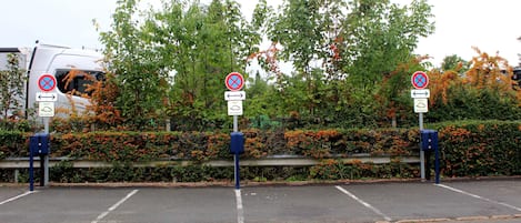 Un estacionamiento con varios carteles que indican prohibido estacionar y puntos de carga para vehículos eléctricos.