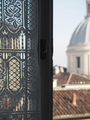 A lace window with a view of a building with a dome.