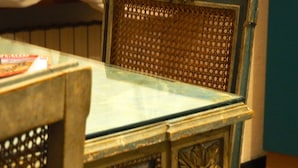 A vintage-style table with a glass top and ornate metal detailing.