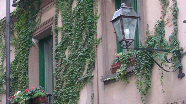 A building with a balcony, a window with a hanging lantern, and a flower box.