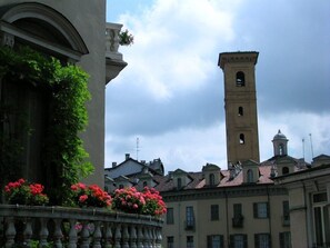 A historic building with a prominent tower and a balcony with flowers.