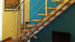 A staircase with a glass enclosure, a painting on the wall, and a television on a stand.