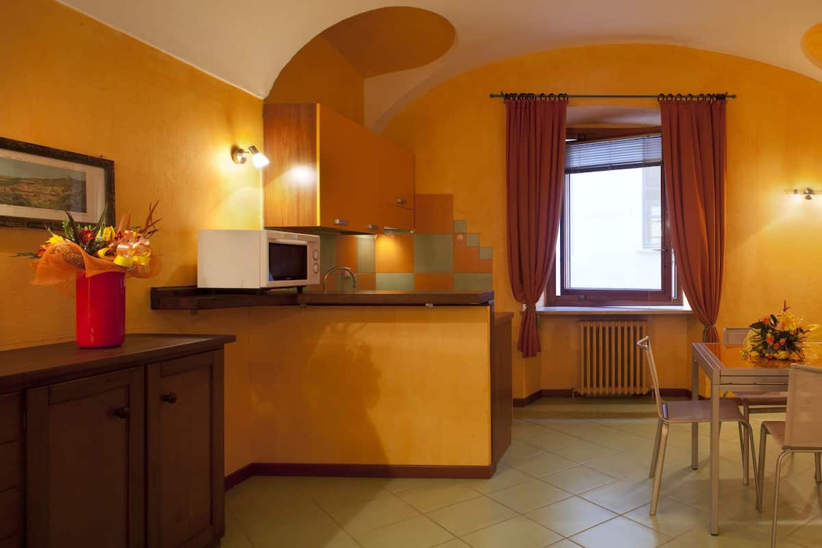 A compact kitchen with a dining area, featuring a microwave, refrigerator, and a dining table with chairs.