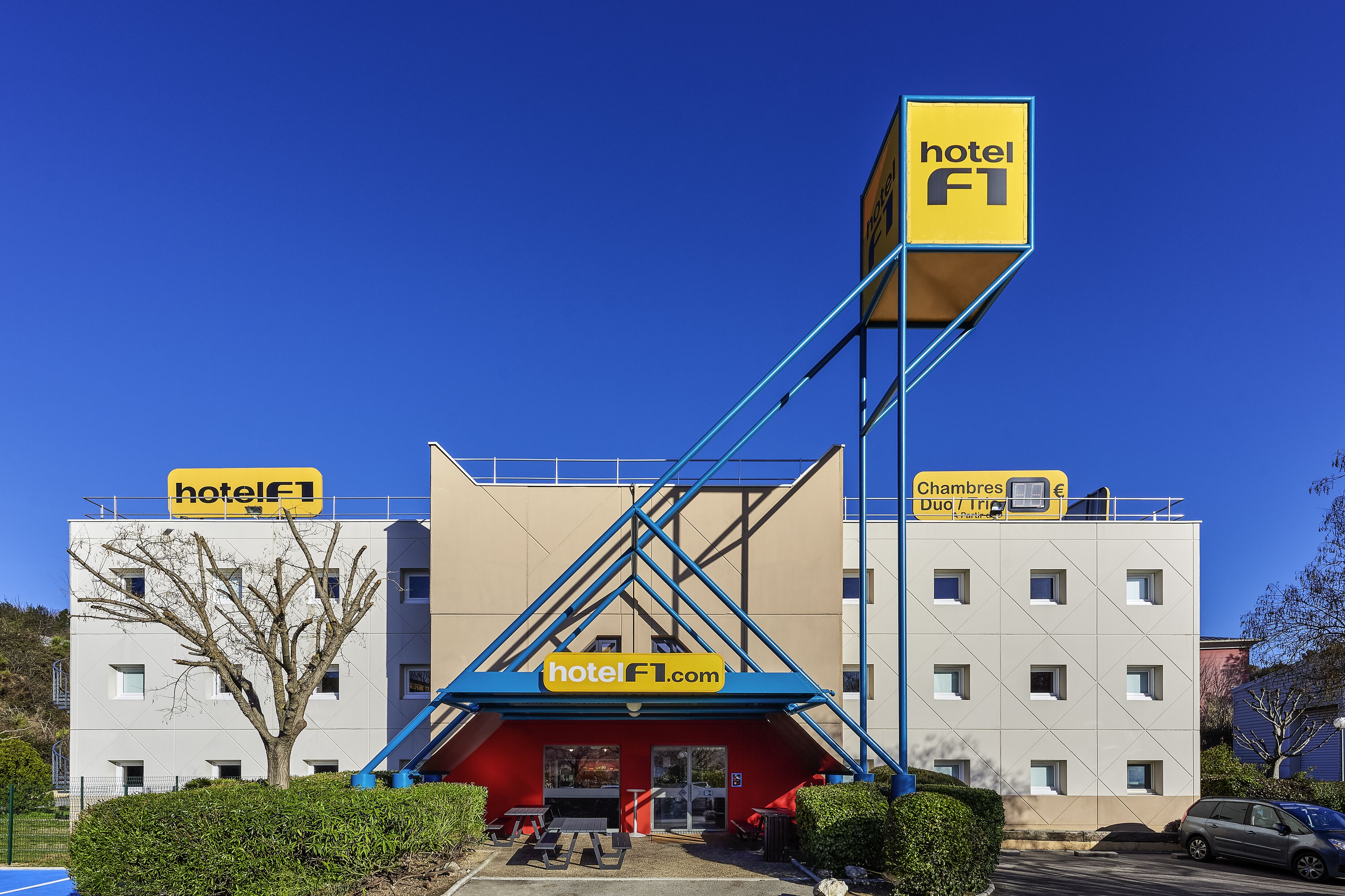 Een hotel met een opvallend blauw en geel bord, een rode entree en een modern architectonisch ontwerp.