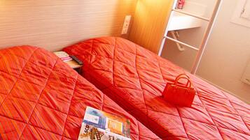 A bunk bed with a red quilted bedspread and a magazine on the lower bunk.
