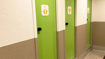 Ein Korridor mit grünen Türen, jede mit einem weißen Schild, das auf eine Herrentoilette hinweist.