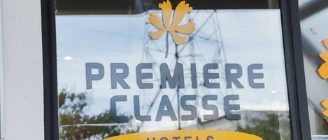 Una ventana con el texto "PREMIERE CLASSE HOTELS" y un logo de hoja de arce.