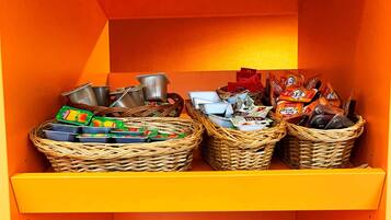 A small storage area with wicker baskets containing snacks and drinks, a clear plastic box, and a small white container.
