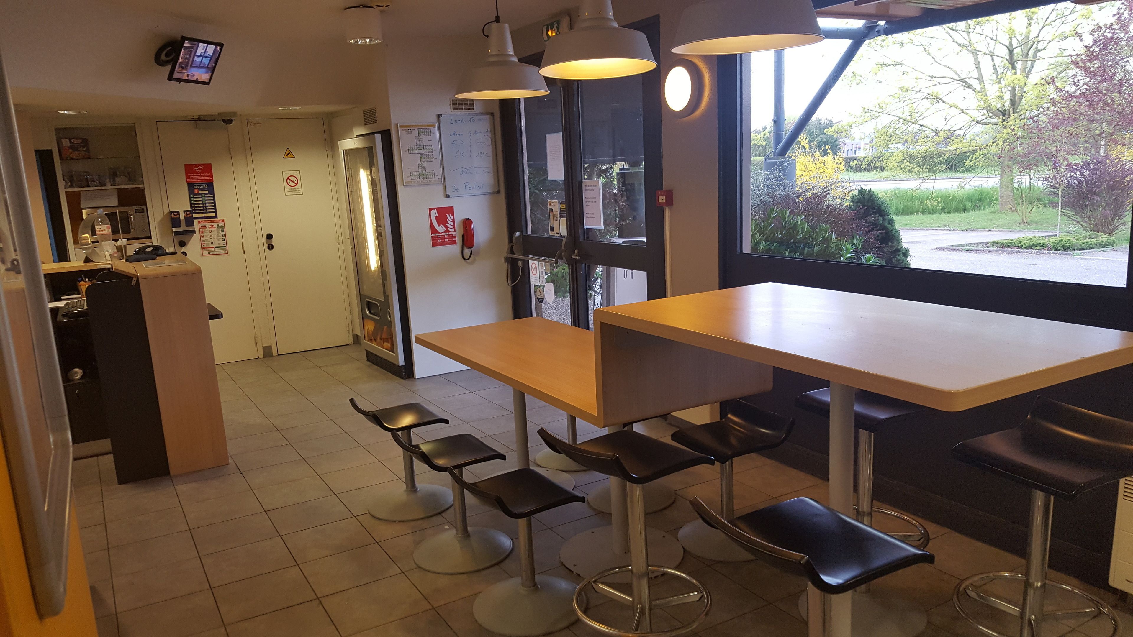 A restaurant interior with a counter, bar stools, and a large window offering a view of the outdoors.