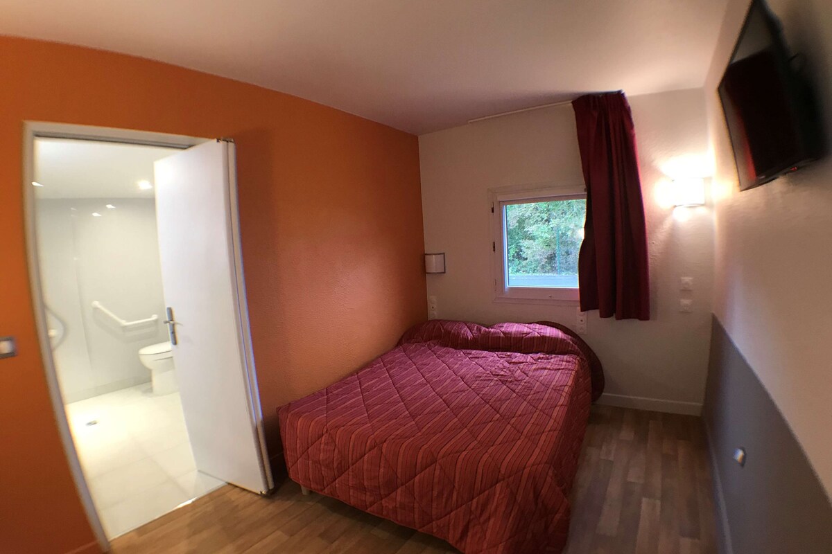 Une chambre à coucher avec un lit, une fenêtre avec des rideaux et une porte donnant sur une salle de bain.