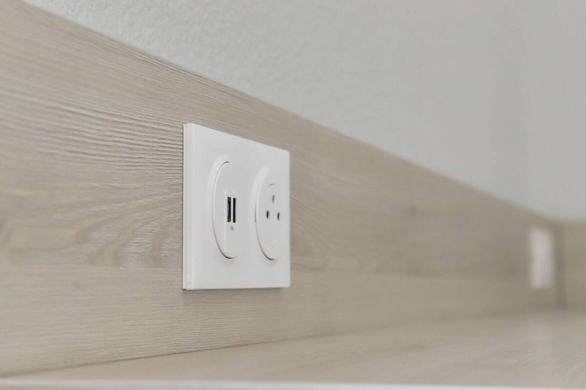 Une prise électrique blanche sur un mur en bois.