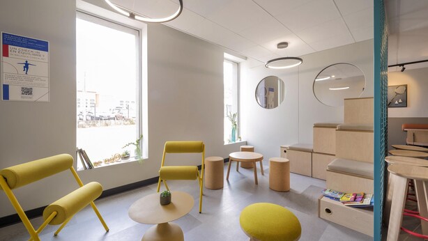 A modern, well-lit room with yellow chairs, a small table, and a bookshelf. - ibis budget Forbach Centre (Forbach)