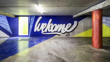 Een ondergrondse parkeergarage met een 'Welcome'-bord, betonnen pilaren en een schuin dak.