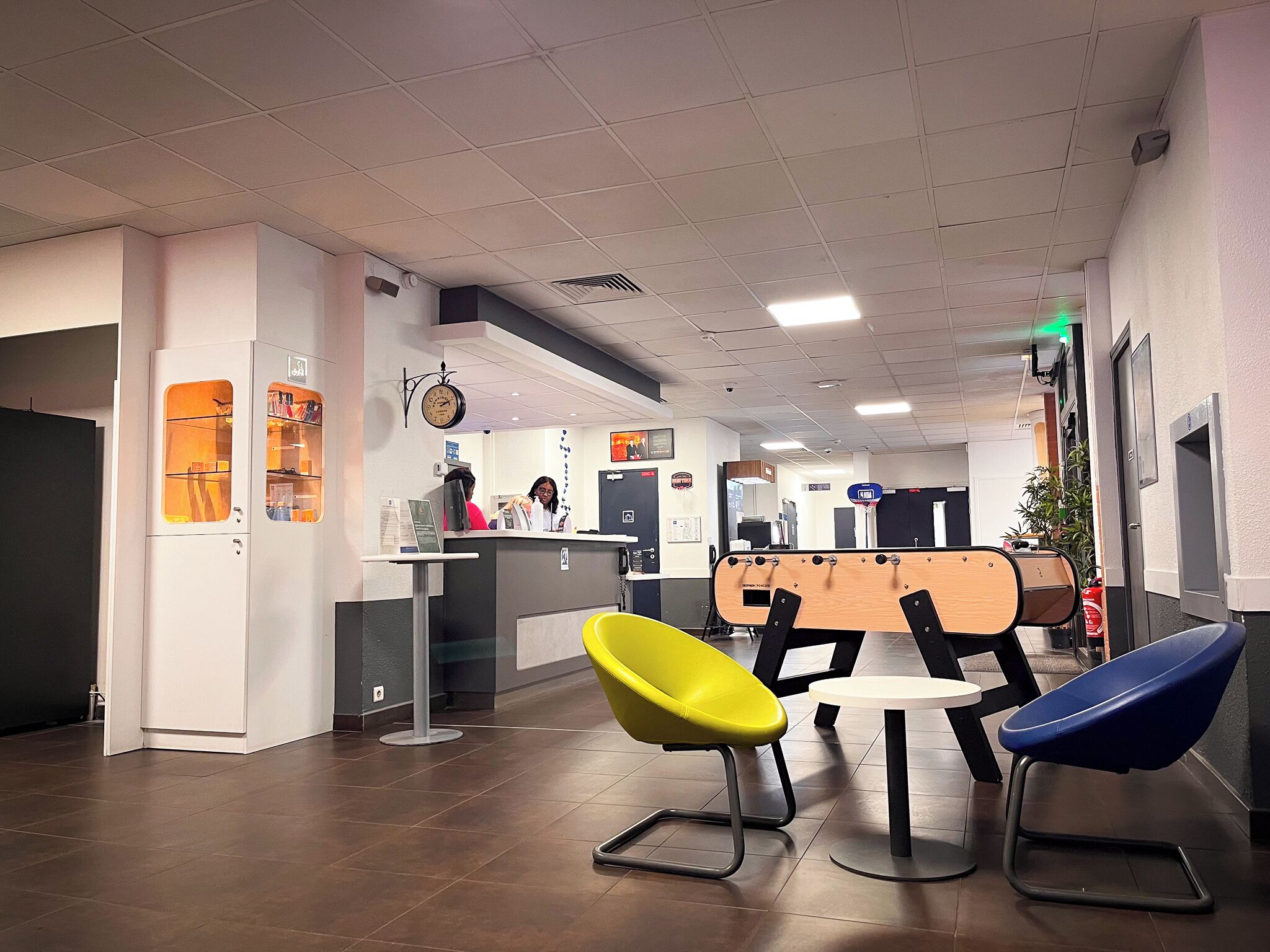 A reception area with a counter, two chairs, a clock, and a door.
