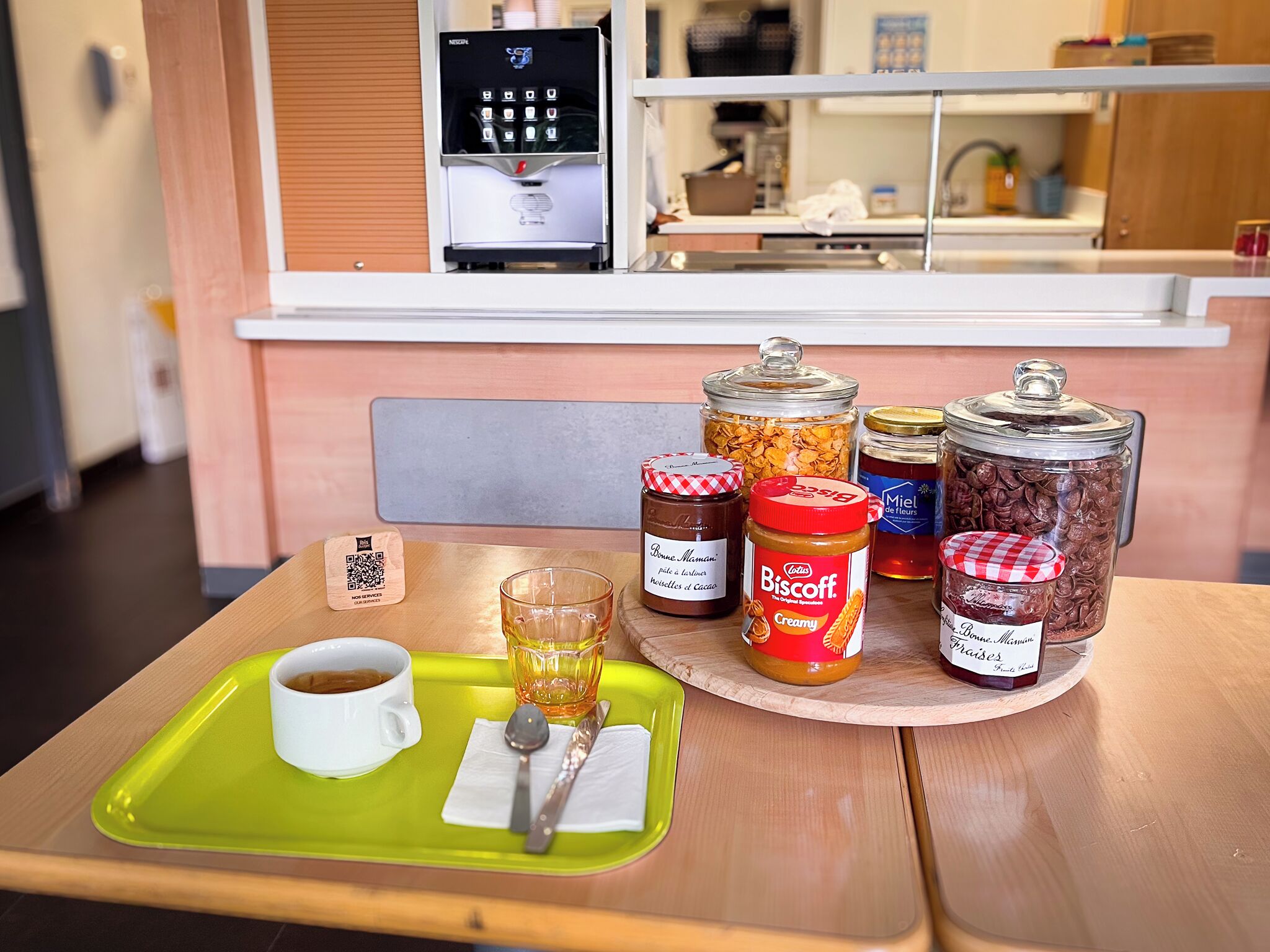 A breakfast tray with a cup of coffee, a glass of juice, and various condiments on a wooden table.