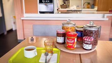 A breakfast tray with a cup of coffee, a glass of juice, and various condiments on a wooden table.