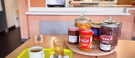Un plateau de petit-déjeuner avec une tasse de café, un verre de jus de fruits et divers condiments, posé sur une table en bois.