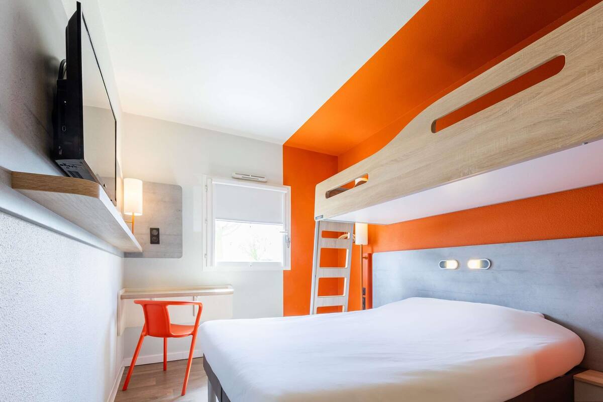 Una habitación de hotel moderna con una cama, un escritorio y una silla.