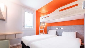 Una habitación con dos camas, incluida una litera, una ventana y un escritorio.