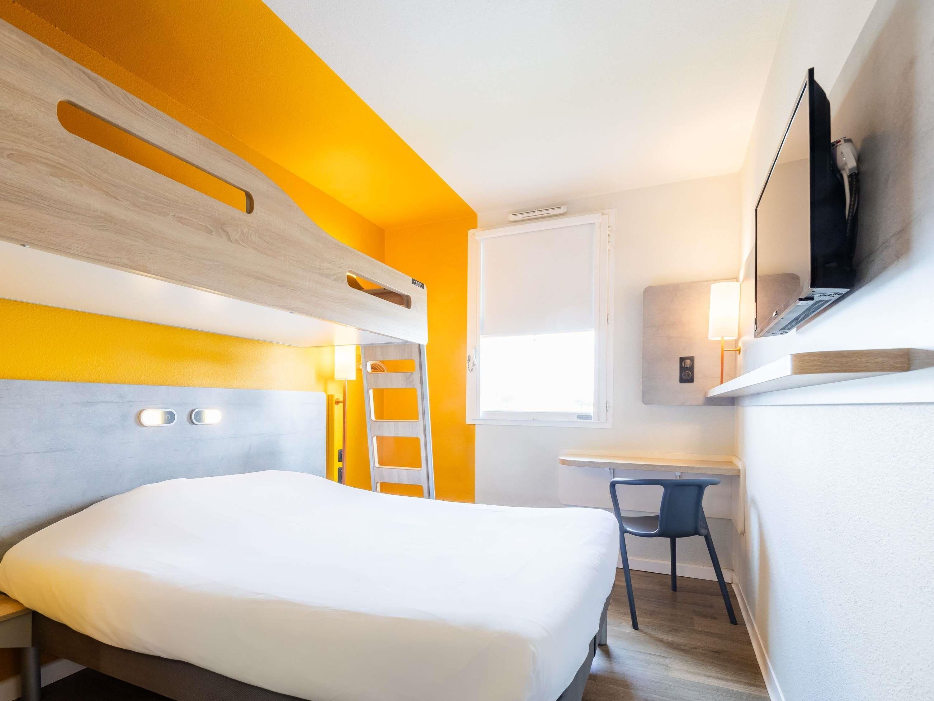 Een hotelkamer met een bed, een bureau, een stoel, een televisie en een raam.