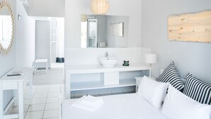 A modern hotel room with a large bed, a white vanity, and a view of the balcony. - Akra Morea Hotel & Residences by GHH (Monemvasia)