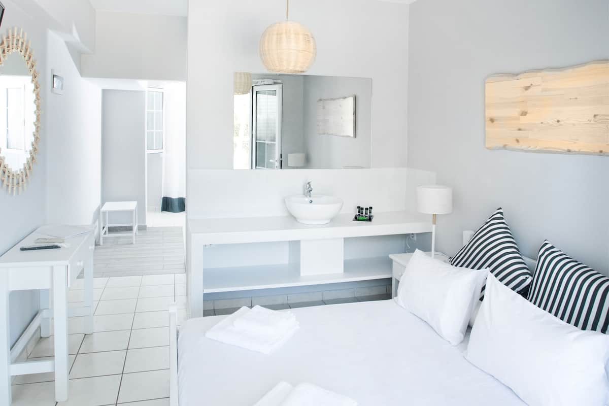 Un hotel moderno con una cama grande, un tocador blanco y vistas al balcón.