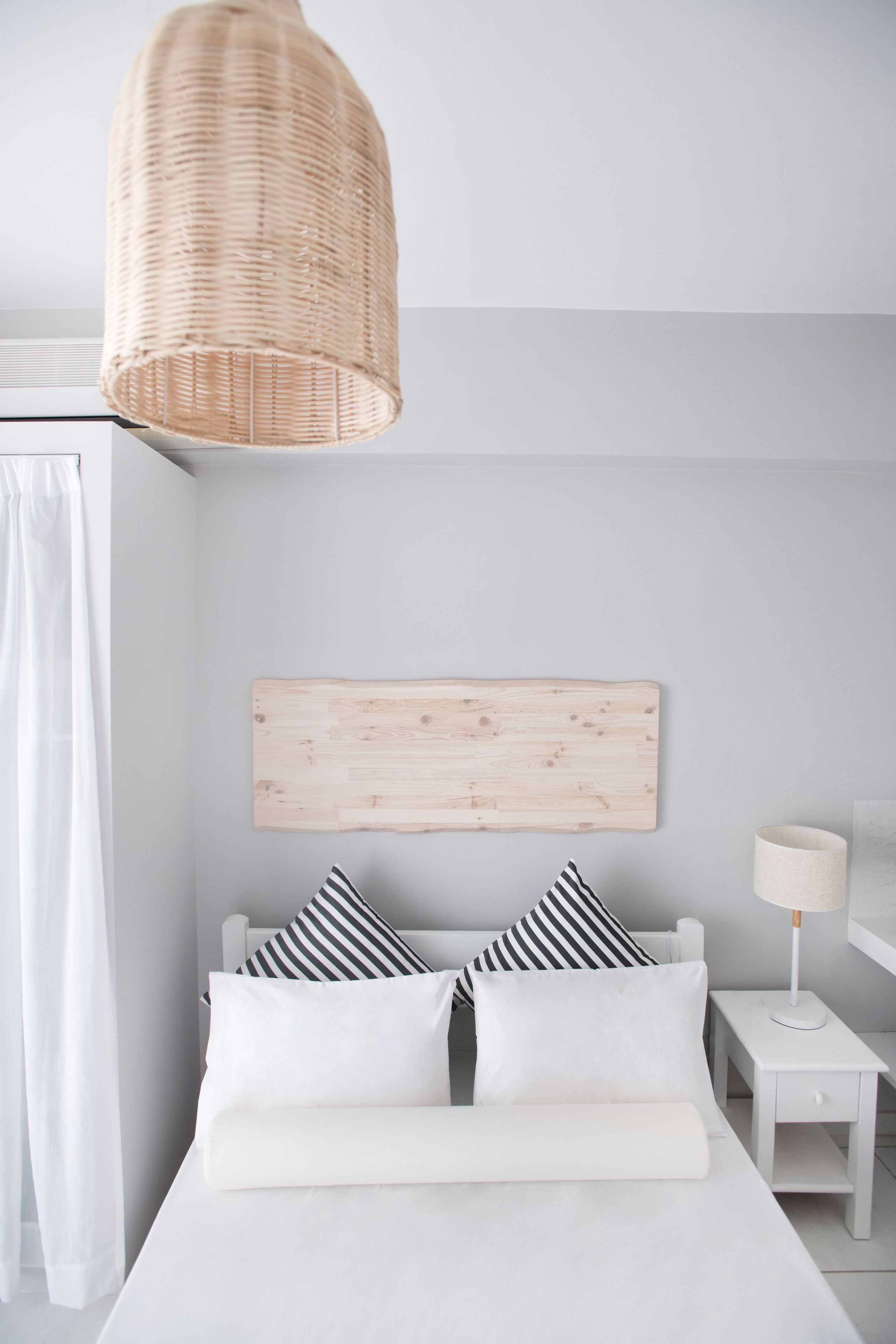 A minimalist bedroom with a bed, a bedside table, a lamp, and a hanging light fixture.