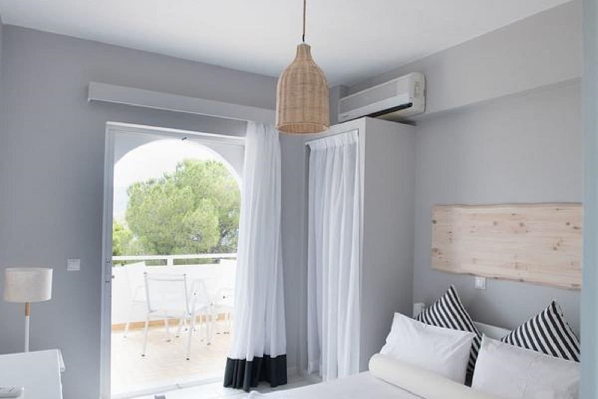 A modern bedroom with a bed, a desk, and a view of the outdoors.