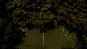 An aerial view of a sports court surrounded by dense trees. - Akra Morea Hotel & Residences by GHH (Monemvasia)