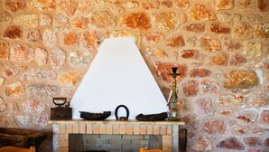 A stone wall with a fireplace, a white triangular object on top, and a hookah on the right. - Akra Morea Hotel & Residences by GHH (Monemvasia)