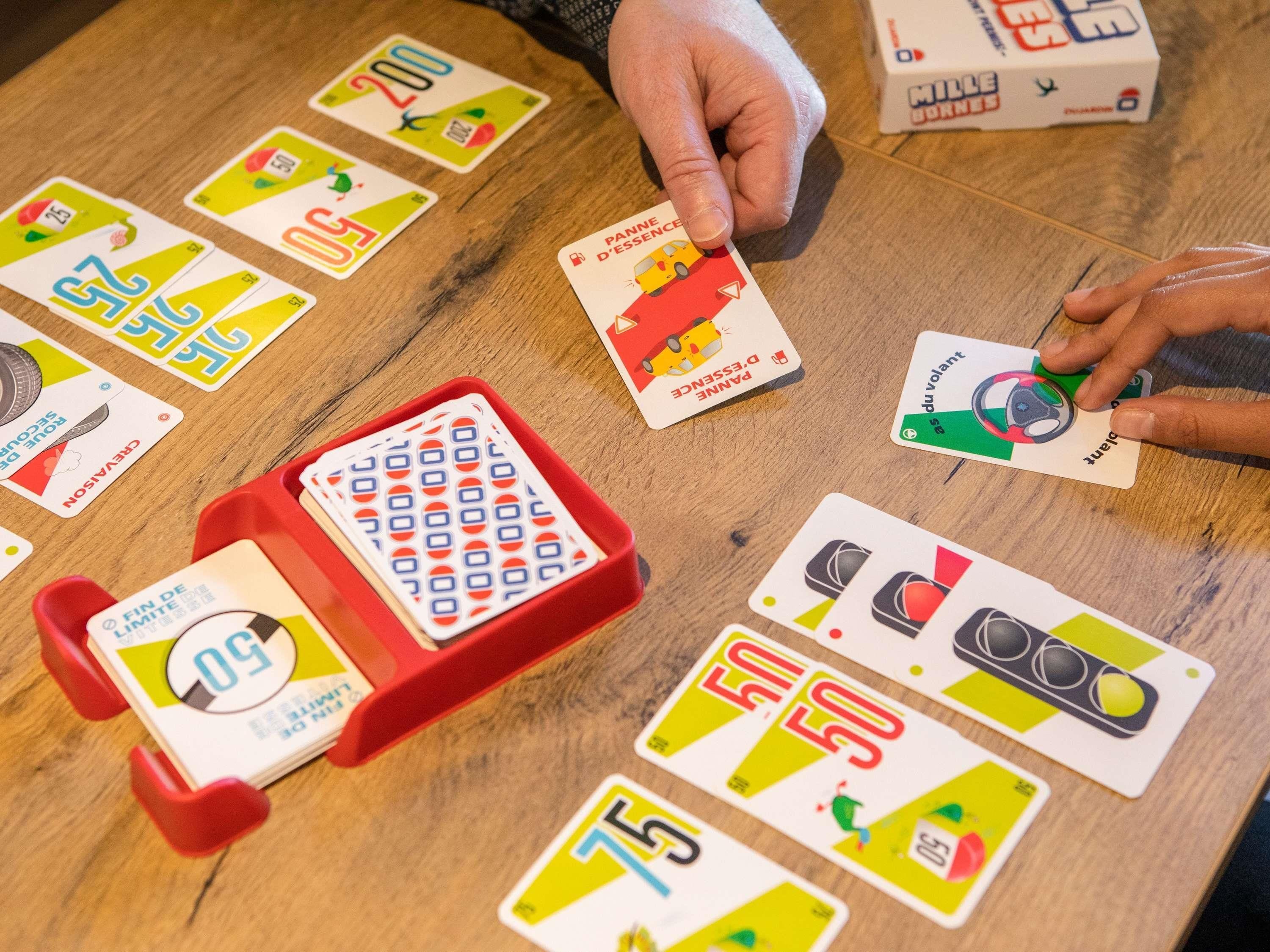 A wooden table with various playing cards and a red tray.