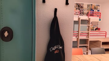 Una habitación con literas, una mesa de madera y una pared decorada con carteles.