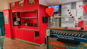 A red reception desk with a sign about keeping distance and a new formula. - hotelF1 Beauvais (Beauvais)