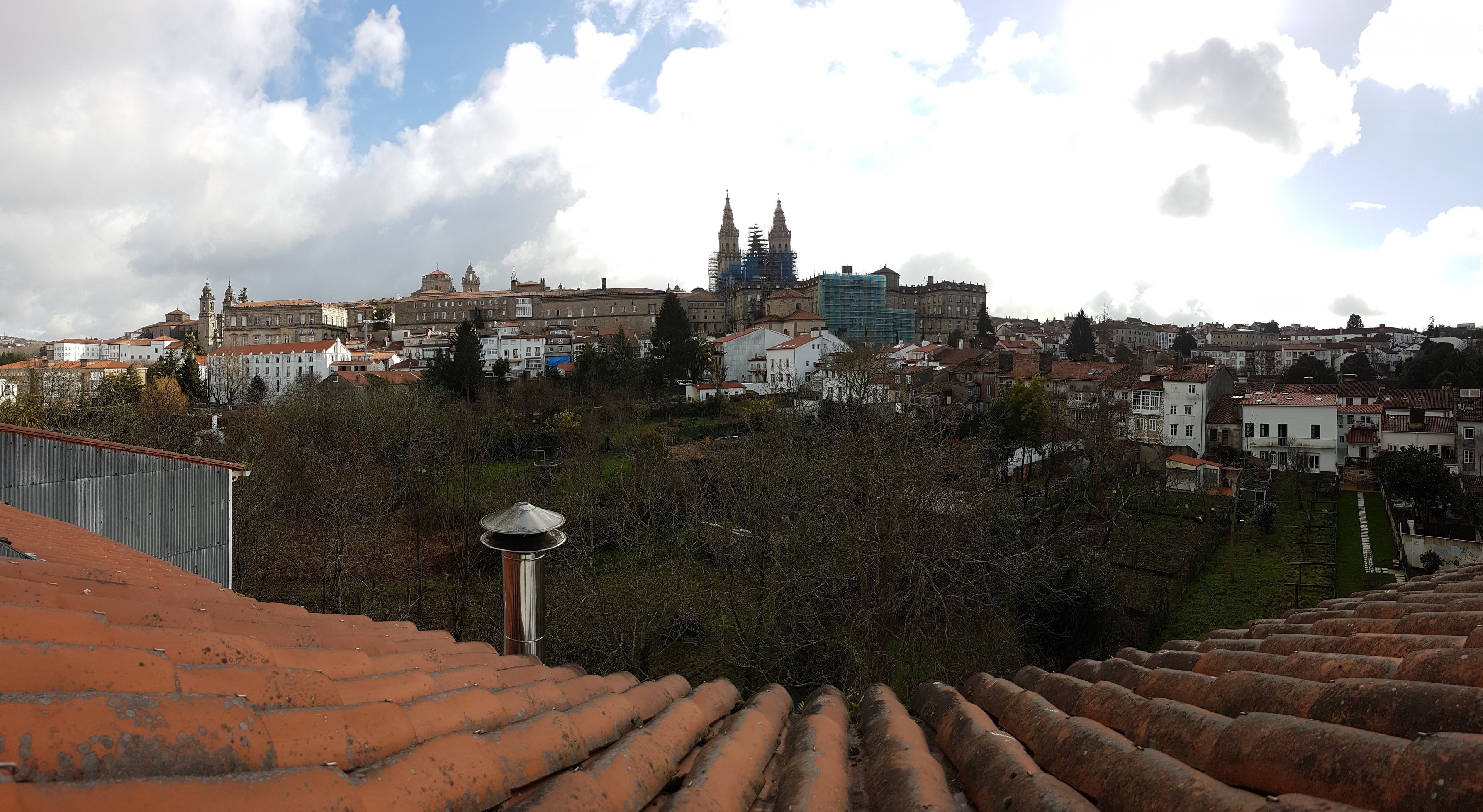 Panorama urbano con edifici storici, tra cui una chiesa in evidenza con due torri gemelle, e un edificio moderno in costruzione.
