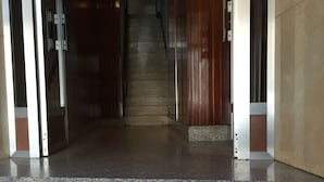 A marble staircase leading to a wooden door, with a light fixture above. - Hostal Costa Azul (Santiago de Compostela)