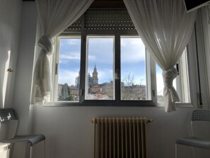 A room with a large window, white curtains, a radiator, and two chairs. - Hostal Costa Azul (Santiago de Compostela)