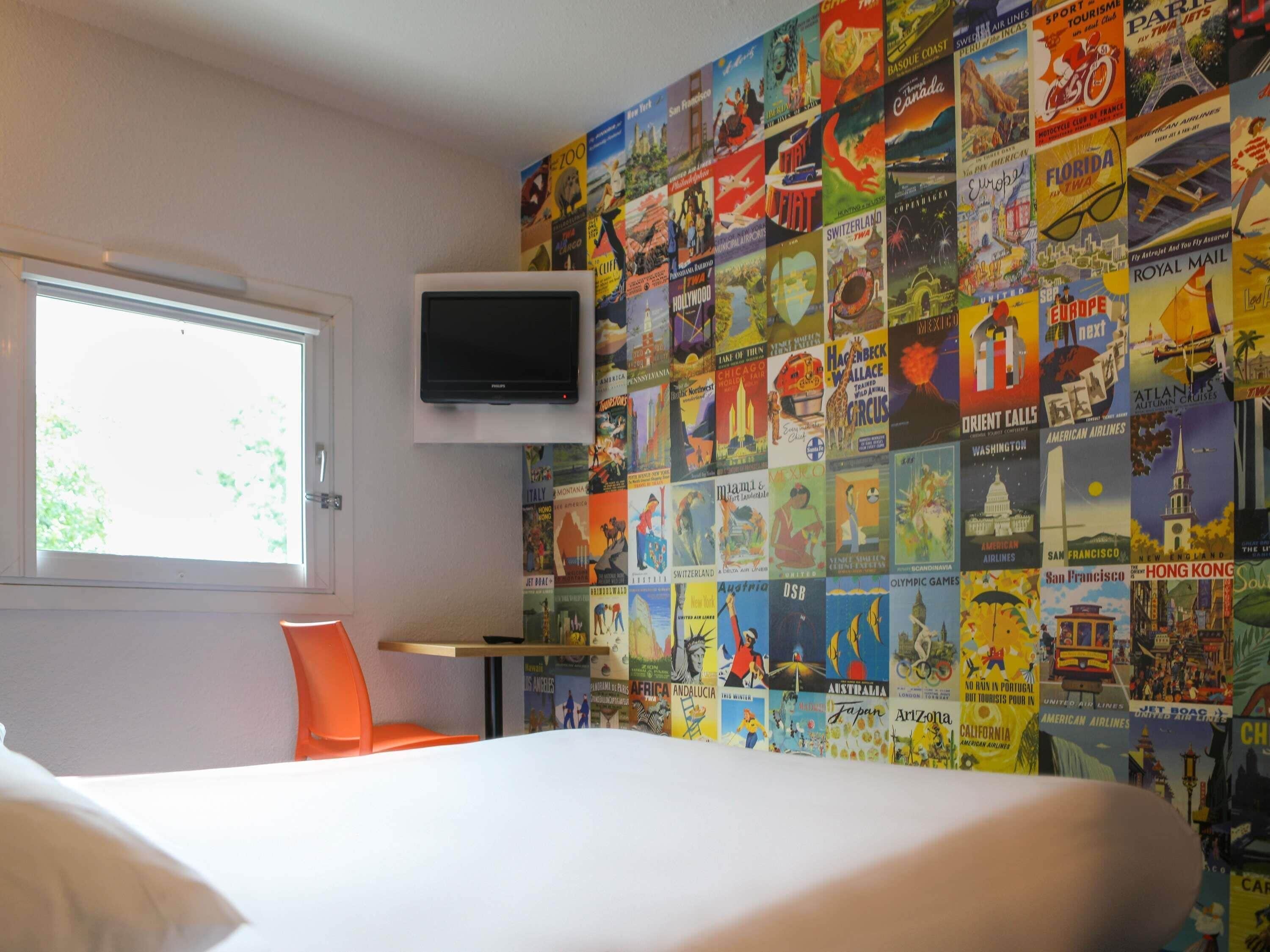 Une chambre d’hôtel avec un grand lit, un téléviseur fixé au mur et une fenêtre donnant sur un paysage verdoyant.