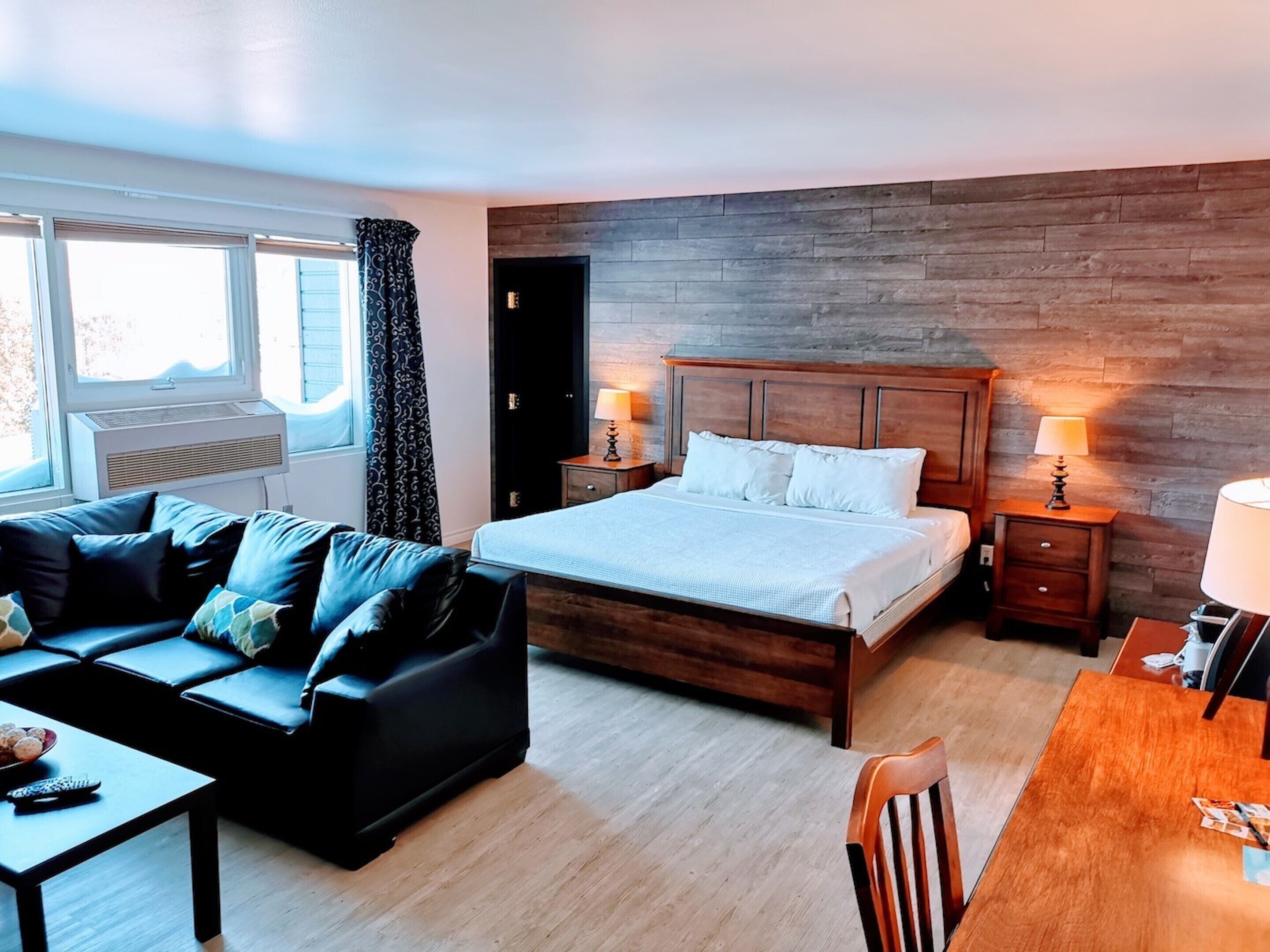 Una habitación de hotel con cama, sofá, mesa de madera y una silla.