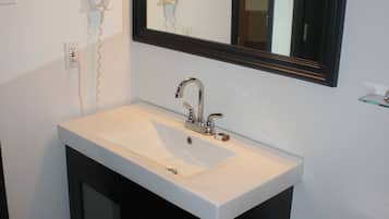 A bathroom with a white sink, black cabinets, a mirror, and a toilet.
