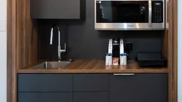 A modern kitchen with a built-in microwave, stainless steel sink, and a coffee machine.