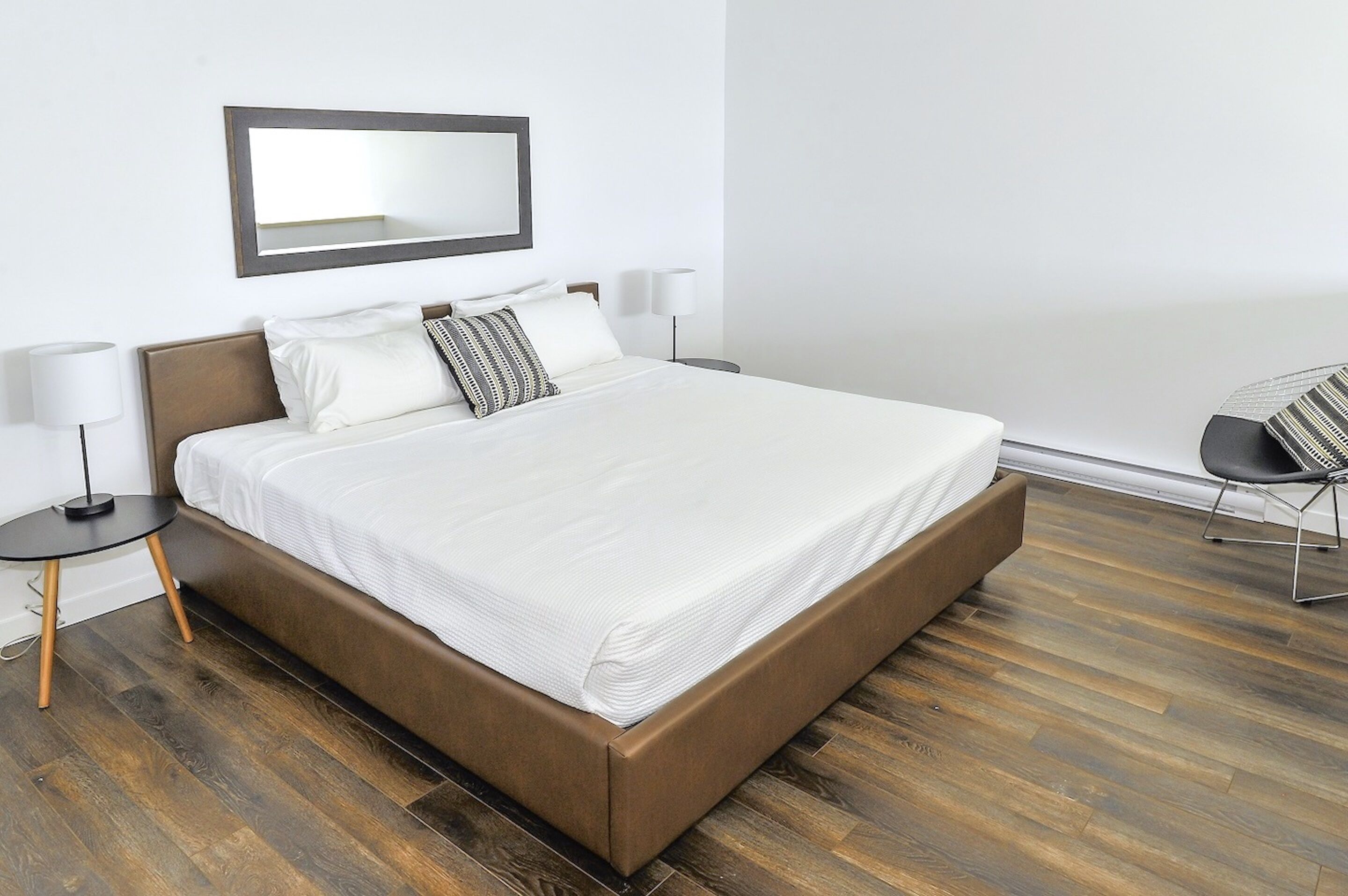 Una habitación de hotel moderna con una cama grande, una mesita redonda y una silla.
