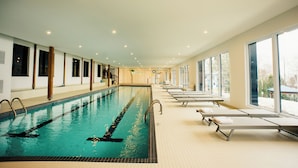A large indoor swimming pool with clear lanes, adjacent sun loungers, and large windows offering views of the outside. - Auberge des Îles (Saint-Gedeon)