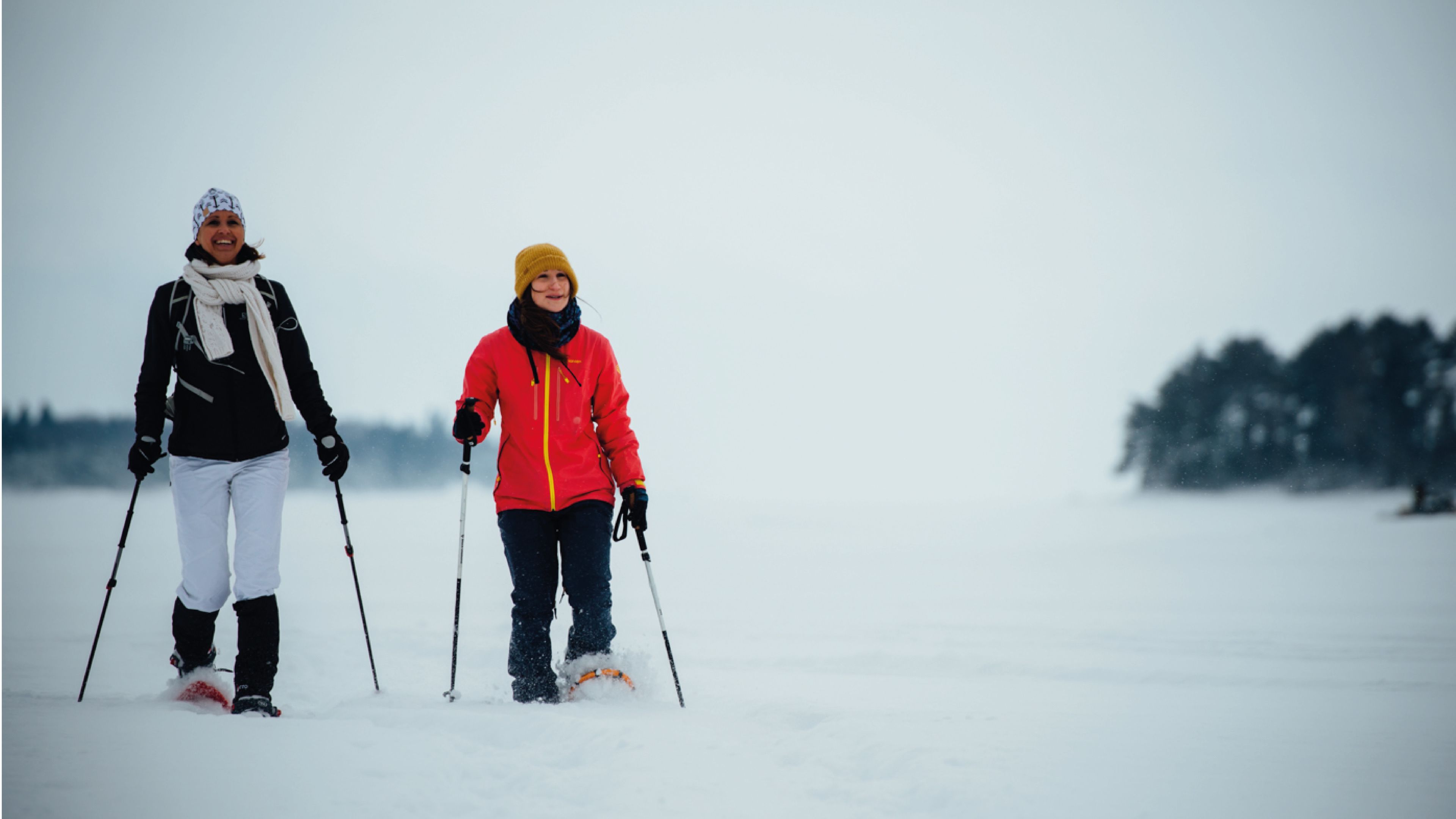 Twee personen skiën in een besneeuwd landschap.