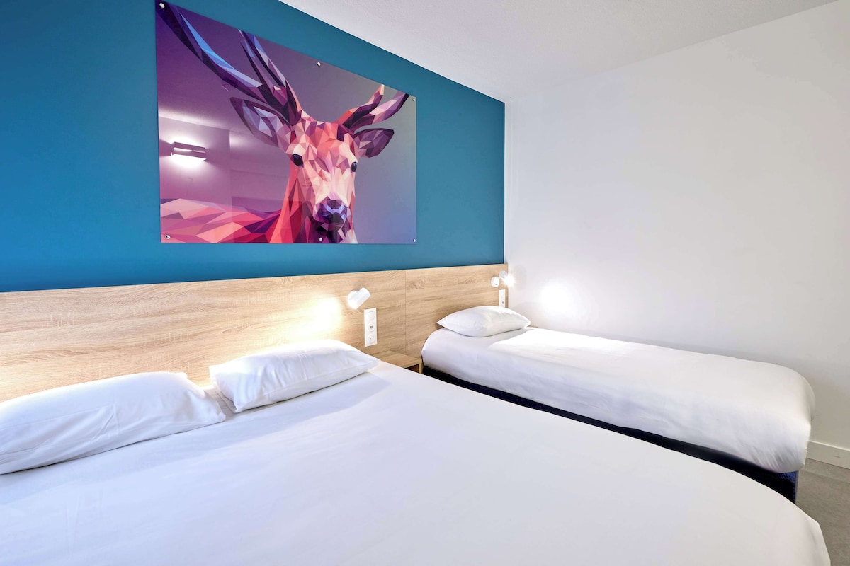Habitación de hotel con dos camas, cabecero de madera y un cuadro abstracto grande en la pared.