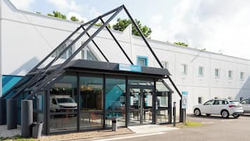 Kyriad features a sleek glass facade and a black roof, complemented by a white wall and blue trim.