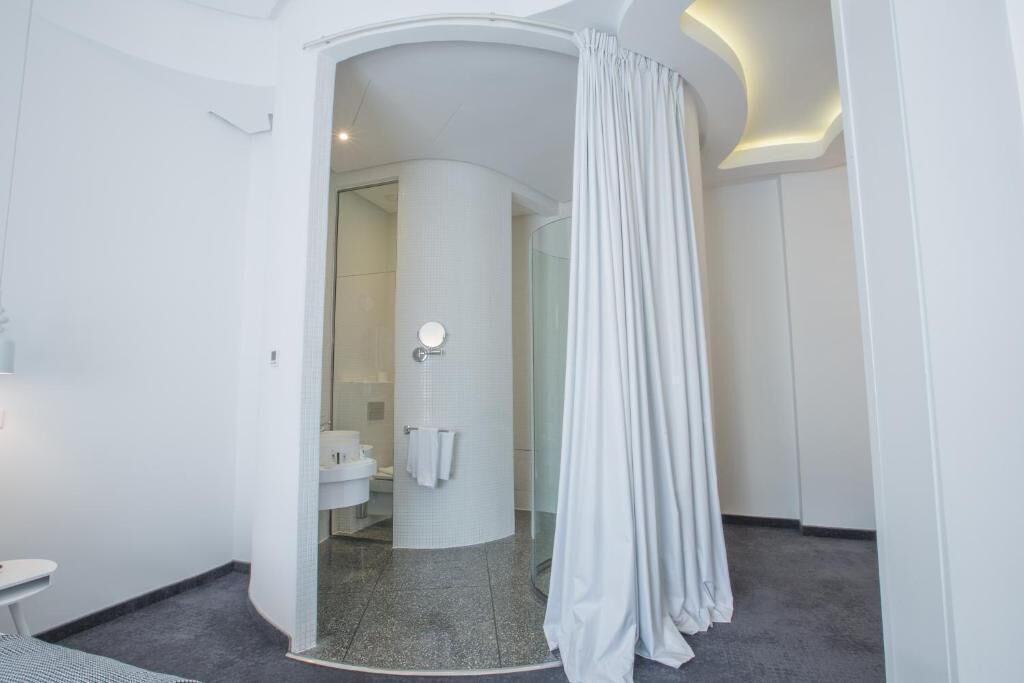 A modern bathroom with a curved shower area, a glass door, and a white sink.