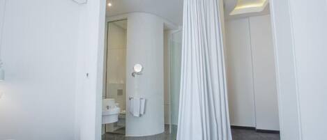 A modern bathroom with a curved shower area, a glass door, and a white sink.