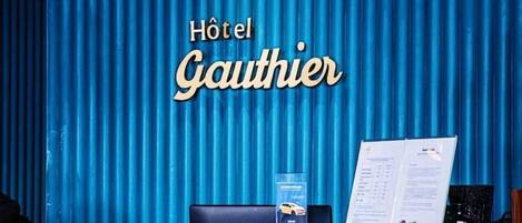 A hotel reception desk with a blue curtain backdrop, a menu, and a car service brochure.
